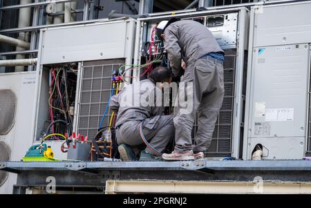 März 13. 2023 – Tokio, Japan: Japanische Ingenieure reparieren eine Klimaanlage mit Kabeln in einer Straße in Tokio, Japan Stockfoto