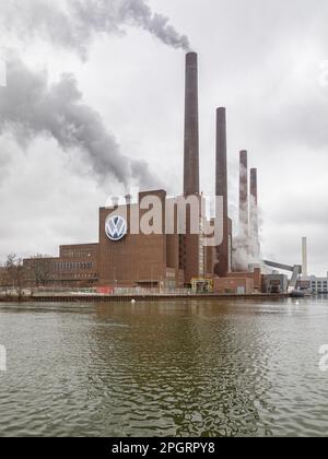 Wolfsburg, Deutschland – 9. März 2023: Kraftwerk des Volkswagen-Werks am Mittelland-Kanal, vorbeifahrendes Frachtschiff Stockfoto