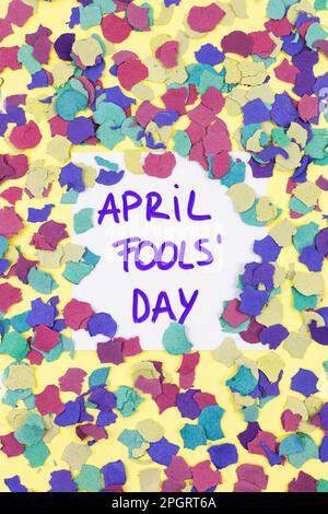 APRIL-NARRENTAG. Flache Ansicht von April Fools in vertikaler Draufsicht mit Aufkleber mit farbenfrohem Konfetti auf gelbem Hintergrund. Witz, Schwindel, Streich, Party, Spaß Stockfoto