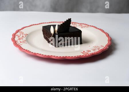 Teller mit Scheibe leckeren hausgemachten Schokoladenkuchen auf dem Tisch Stockfoto