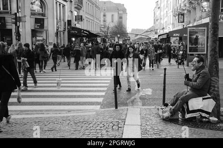 PARIS, FRANKREICH - 12. MÄRZ 2016: Mann in der Maske Angeln (Betteln) Geld im Stadtzentrum. Bettler arbeiten in beliebten Einkaufs- und Touristenattraktionen. Schwarz weiß Stockfoto