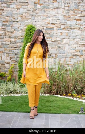 Weibliches Model, das sich draußen in einem Sommerkleid mit indischem pakistanischem, asiatischem, traditionellem Salwar-Kameez posiert Stockfoto