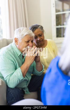 Traurige Gruppe verschiedener Senior-Freunde, die im Wohnzimmer sitzen und während der Gruppentherapie zuhören. Seniorenleben, Freundschaft und Unterstützung. Stockfoto