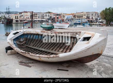 Hafengebiet Rethymnon, Kreta, Griechenland mit Boot, das die Hellbahn mit Leuchtturm und Piratenboot in dieser Hafenszene hochgezogen hat. Stockfoto