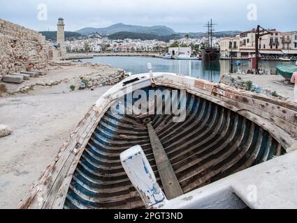 Hafengebiet Rethymnon, Kreta, Griechenland mit Boot, das die Hellbahn mit Leuchtturm und Piratenboot in dieser Hafenszene hochgezogen hat. Stockfoto