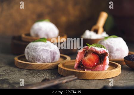 Japanischer Mochi oder Reiskuchen gefüllt mit roten Bohnen und Erdbeeren, Minzblätter oben drauf. Traditioneller japanischer Reiskuchen. Stockfoto