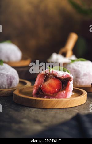 Japanischer Mochi oder Reiskuchen gefüllt mit roten Bohnen und Erdbeeren, Minzblätter oben drauf. Traditioneller japanischer Reiskuchen. Stockfoto