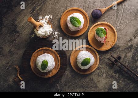 Japanischer Mochi oder Reiskuchen gefüllt mit roten Bohnen und Erdbeeren, Minzblätter oben drauf. Traditioneller japanischer Reiskuchen. Stockfoto