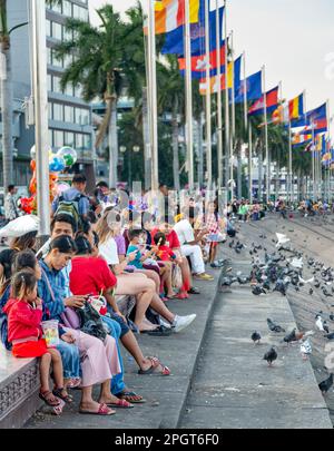 Phnom Penh, Kambodscha-Dezember 23. 2022: In der relativ kühlen frühen Dämmerung sitzen viele Familien, Freunde und Tauben entlang der Flussufer, bei Sisowath Stockfoto