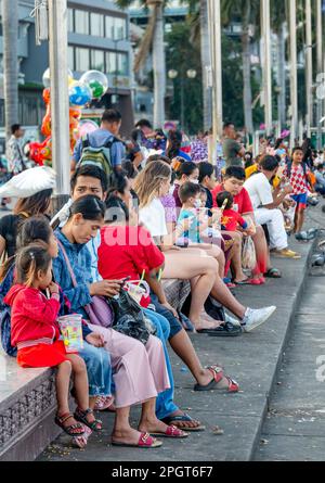 Phnom Penh, Kambodscha-Dezember 23. 2022: In der relativ kühlen frühen Dämmerung sitzen viele Familien, Freunde und Tauben entlang der Flussufer, bei Sisowath Stockfoto