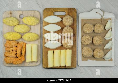 Verschiedene hausgemachte Halbfertigprodukte auf Holzbrettern. Gefrorene Schnitzel, Knödel, Nuggets. Zubereitungen aus hausgemachter Nahrung. Stockfoto