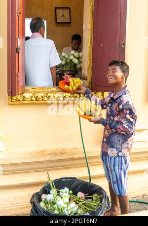 Phnom Penh, Kambodscha-Dezember 23. 2022: Ein männlicher Arbeiter im Preah Ang Dorngkeu Heiligen Tempel, sammelt Früchte und Blumen, Opfer für den buddhistischen Schrein. Stockfoto