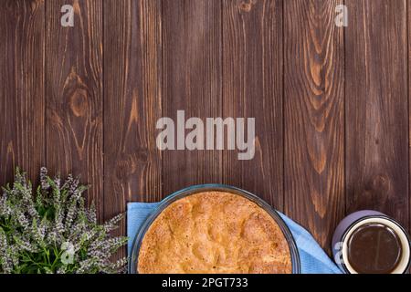 Frisch gebackener Kuchen auf einer dunklen Holzfläche mit einer Tasse Tee und Lindenblüte. Platz für eine Inschrift. Blick von oben. Stockfoto