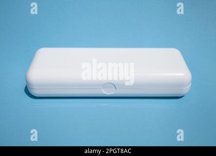 Weiße rechteckige Kunststoffbox mit isoliertem Kopierbereich auf blau. Glattes, glänzendes Gehäuse mit Deckel für ein Produktmodell Stockfoto