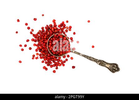 Nahaufnahme ein Vintage-Metalllöffel voller rot-rosa Pfefferkörner verschüttet und auf weißem Hintergrund isoliert verteilt, erhöhte Ansicht von oben, direkt Stockfoto