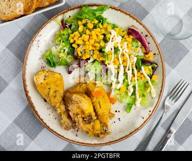Gebackene Hähnchenteile mit Salat und Mais Stockfoto