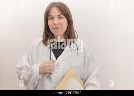 Junger Arzt mit weißem Mantel und Stethoskop, weißem Hintergrund und Kopierraum Stockfoto