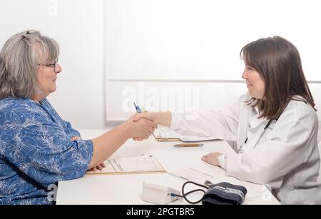 Der Arzt begrüßt ihre Patientin vor der Sprechstunde Stockfoto