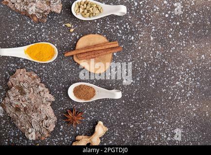 Natürliche Gewürze aus Kurkuma, Kardamom, Zimt, getrocknetem Ingwer, Sternanis mit Kopierraum. Gewürze auf schwarzem Hintergrund. Stockfoto