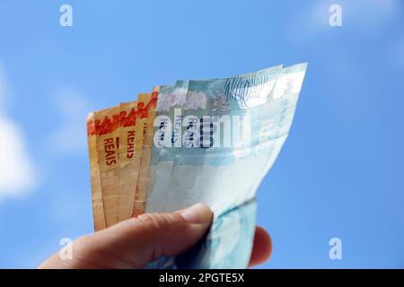 Mit brasilianischen echten Banknoten mit blauem Himmel im Hintergrund - mehrere hundert Banknoten Stockfoto