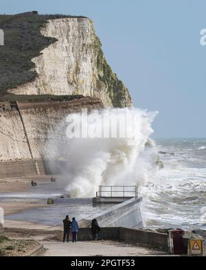 Brighton UK 24. März 2023 - Wanderer beobachten riesige Wellen, die über den undercliff Walk in Saltdean östlich von Brighton stürzen, mit starken Winden vermischt mit der Sonnenvorhersage für die Südküste heute : Credit Simon Dack / Alamy Live News Stockfoto