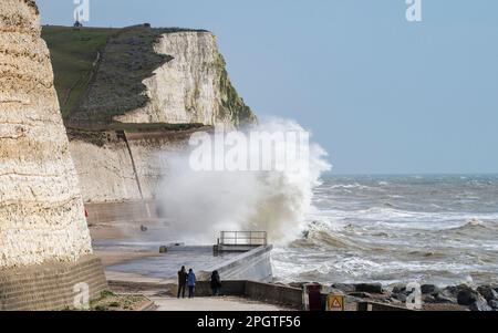 Brighton UK 24. März 2023 - Wanderer beobachten riesige Wellen, die über den undercliff Walk in Saltdean östlich von Brighton stürzen, mit starken Winden vermischt mit der Sonnenvorhersage für die Südküste heute : Credit Simon Dack / Alamy Live News Stockfoto