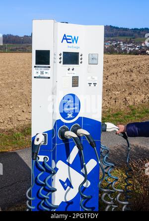 Seengen, Schweiz - 23. Februar 2023: Frau, die einen elektrischen Ladeanschluss des Ladegeräts der AEW-Firma hält, um ein Fahrzeug aufzuladen. Stockfoto