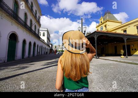 Tourismus in Santos, Brasilien. Junge Reisende, die zwischen dem Palast des Pelé-Museums und der historischen Straßenbahnhaltestelle, Touristenattraktionen von Santo, spazieren gehen Stockfoto