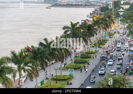 Viele kambodschanische Autos, Motorräder und Khmer Menschen bei Sonnenuntergang, geschäftigste Tageszeit. Sisowath Quay, eine beliebte Strip und Fußgängerzone, Leute und Familien CO Stockfoto