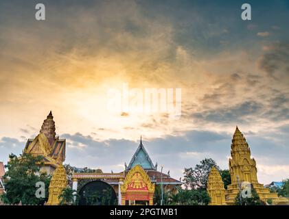 Goldfarbener Himmel, wenn die Sonne hinter der berühmten Touristenattraktion der kambodschanischen Hauptstadt city.beautiful Khmer-Pagoden untergeht und sich mit dem pulsierenden Gold an vermischt Stockfoto