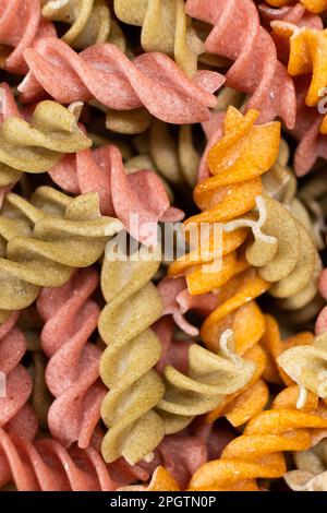 Reisgemüse-Pasta in Spiralform, Draufsicht. Gesunde Reispasta mit Tomaten, Selenera, Karotten und Rüben Stockfoto