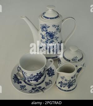 Kompletter Kaffee-, Milch- und Zuckerservice auf weißem Hintergrund. Wunderschöner weißer Dinner-Service mit blauer Dekoration isoliert auf einem weißen Tisch. Milch Stockfoto