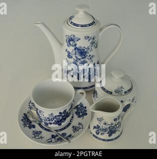 Kompletter Kaffee-, Milch- und Zuckerservice auf weißem Hintergrund. Wunderschöner weißer Dinner-Service mit blauer Dekoration isoliert auf einem weißen Tisch. Milch Stockfoto