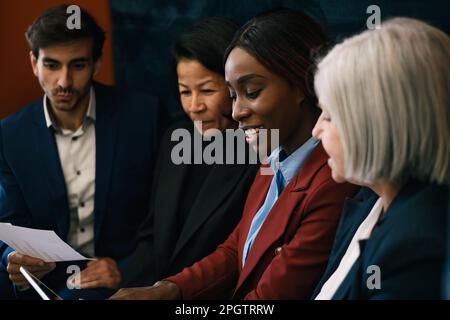 Eine Gruppe von Geschäftsleuten aus verschiedenen Rassen in formellen Outfits, die n sitzen Stockfoto