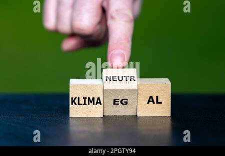 Die Hand dreht den Holzwürfel und ändert den deutschen Ausdruck "klima egal" (Klima ist mir egal) in "klimaneutral" (klimaneutral). Stockfoto