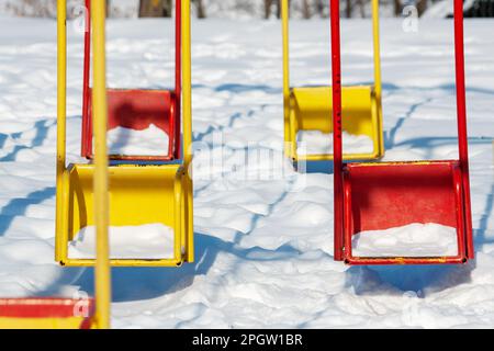 Kinderschaukeln im Winter. Der Begriff der Leere und der Trostlosigkeit Stockfoto