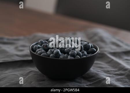 Große Schüssel mit Heidelbeeren auf dem Tisch, flacher Fokus Stockfoto