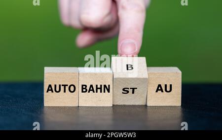 Die Hand wendet den Würfel und ändert den deutschen Ausdruck "Autobahnstau" (Verkehrsstau auf der Autobahn) in "Autobahnbau". Stockfoto