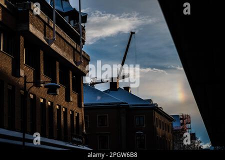 Ein lebendiger, farbenfroher Regenbogen an der Seite zweier roter Ziegelgebäude mit einem hellblauen Himmel im Hintergrund Stockfoto