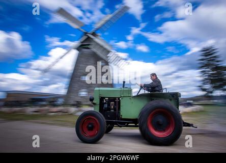 Alt Schwerin, Deutschland. 24. März 2023. Mit dem O & K-Dieseltraktor SA 751 aus dem Baujahr 1939 ist Sven Hermann vor Saisoneröffnung auf dem offenen Gelände mit der Windmühle auf der Straße in der Agrargeschichte Agroneum. Das Landwirtschaftsmuseum ist ein Freiluftmuseum und öffnet seine Türen für interessierte Besucher dieses Wochenende nach den Winterferien. Die Agrargeschichte von Mecklenburg zeigt sich hier von der Mitte des 19. Jahrhunderts bis heute. (Aufnahme mit langer Belichtungszeit) Kredit: Jens Büttner/dpa/Alamy Live News Stockfoto