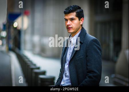 Junger Mann in schwarzem Mantel, sitzt im Winter auf der alten Straße in New York City und denkt nach. Stockfoto