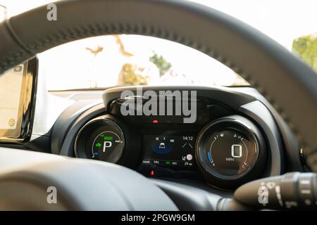 Cockpit-Blick auf ein neues, japanisches Hybrid-Fließheck-Auto. Zeigt das Dual-LCD-Armaturenbrett und einen Teil des großen LCD-Navigationsdisplays auf der linken Seite. Stockfoto