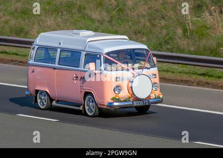 1976 70 70er Jahre Pink VW VOLKSWAGEN „Flower Power“ Lieferwagen, Hochzeitswagen mit Bändern, Blumendekoration und Blumen auf dem Armaturenbrett; Fahrt auf der Autobahn M61 UK Stockfoto