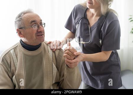 Fürsorgliche Krankenschwester spricht mit altem Patienten hält seine Hand sitzen im Wohnzimmer bei Homecare Besuch bieten psychologische Unterstützung zuhören klagt Empathie zeigen Stockfoto
