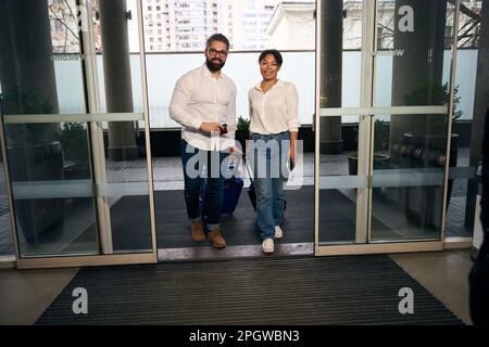 Freudiger Tourist und seine zufriedene, weibliche Begleiterin, die im Hotel ankam Stockfoto