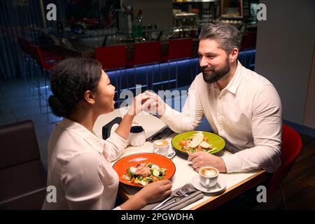 Ein romantischer Mann, der Gesellschaft mit seiner Freundin genießt Stockfoto