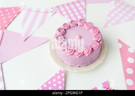 Zarter lavendelrosa Bento-Kuchen auf einem Teller vor einem Hintergrund mit Flaggen für eine Party. Feier, fröhlicher Tag Stockfoto