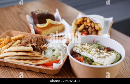 Traditionelles griechisches Fast Food in recyclingfähigem Papiergeschirr. Pita Souvlaki Fleisch, Pommes Frites, weiße Tzatziki Sauce und frischer Salat für lun zubereitet Stockfoto