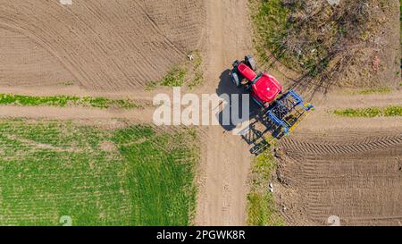 Über der Draufsicht des Traktors, wenn der montierte Sämaschinen, die Egge-Maschine und die Fahrt auf schmutzigen Straßen gezogen werden, an der Kreuzung zum nächsten Feld abbiegt Stockfoto