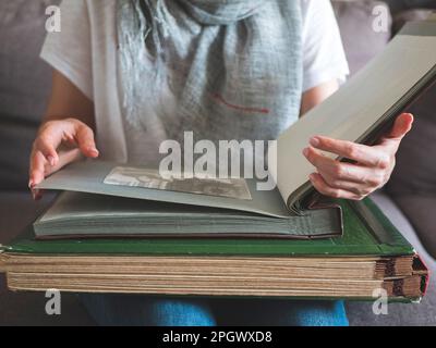 Riesige Fotoalben in den Händen einer Frau, selektiver Fokus. Person zeigt Fotos in einem alten Familienalbum an Stockfoto